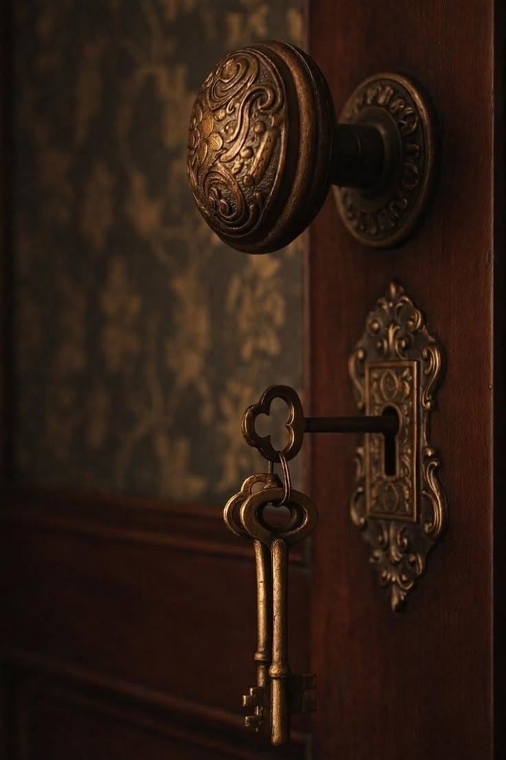An antique brass doorknob with two skeleton keys in the lock