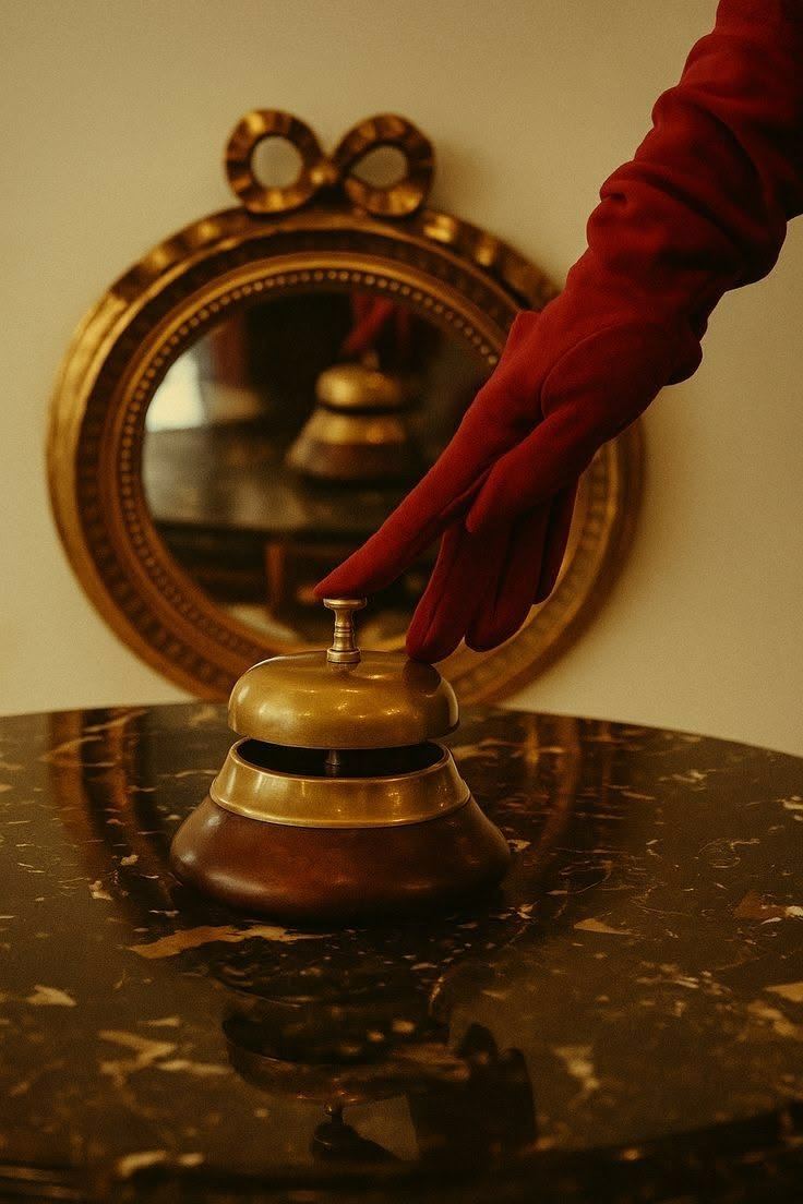 A gloved hand pressing a brass bell on a marble table